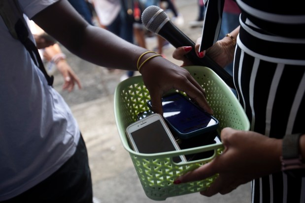A student turns in their cell phone as they enter the school in Rio de Janeiro, Wednesday, Feb. 5, 2025, on the first day of a national ban that restricts the use of smartphones in elementary and high schools. The ban already existed in Rio, but students were allowed to keep their phones in their backpacks. (AP Photo/Bruna Prado)